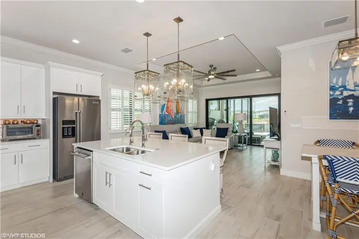 Kitchen with stainless steel appliances, a sink, plenty of natural light, crown molding, and a center island with sink