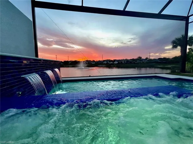 View of swimming pool featuring a water view and a pool with connected hot tub