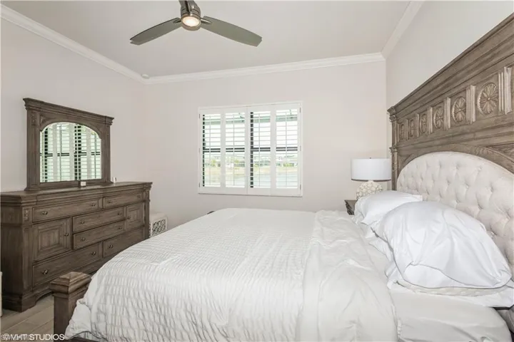 Bedroom with crown molding, multiple windows, light wood-style flooring, and a ceiling fan