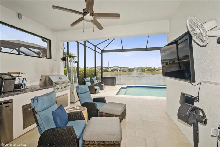 Outdoor pool with an outdoor kitchen, a ceiling fan, a grill, a patio area, and a lanai