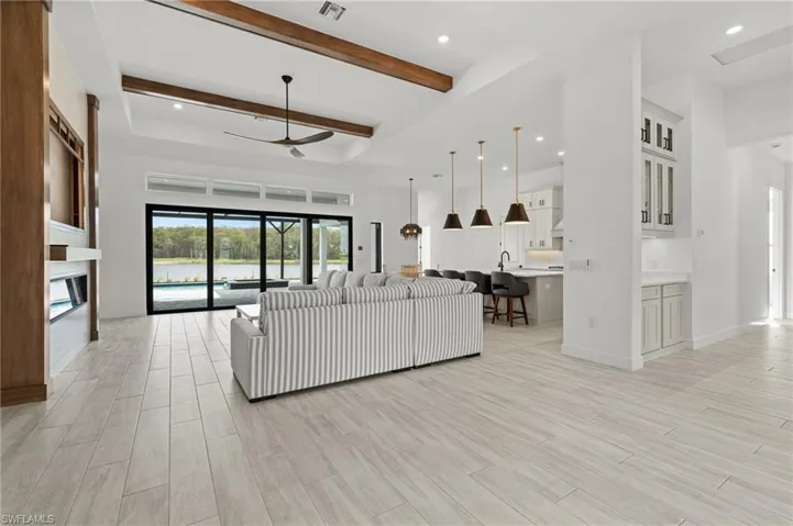 Living area featuring recessed lighting, wood finish floors, a ceiling fan, a glass covered fireplace, and a water view