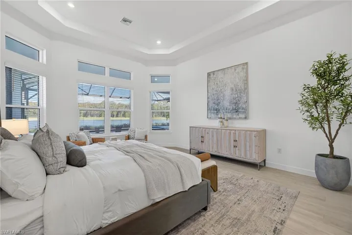 Bedroom with wood finished floors, a raised ceiling, and recessed lighting