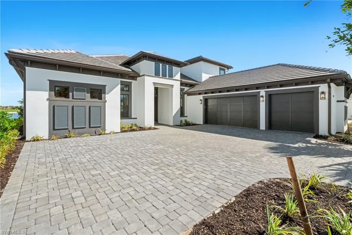 Prairie-style home featuring stucco siding, decorative driveway, a tiled roof, and an attached garage