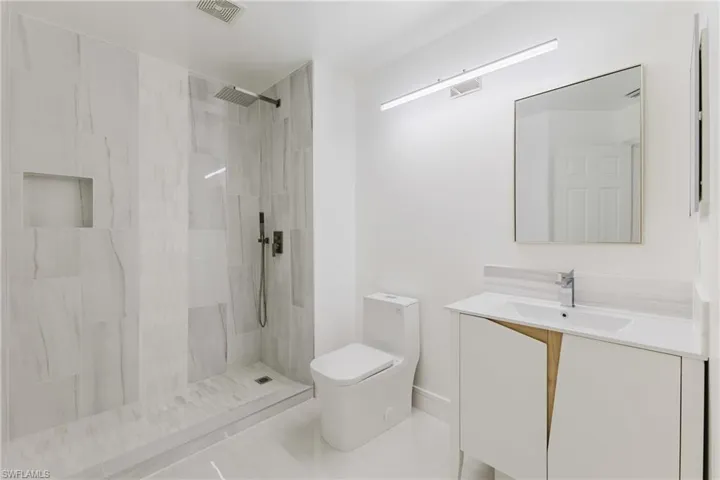Bathroom with vanity, a walk in shower, and tile patterned flooring