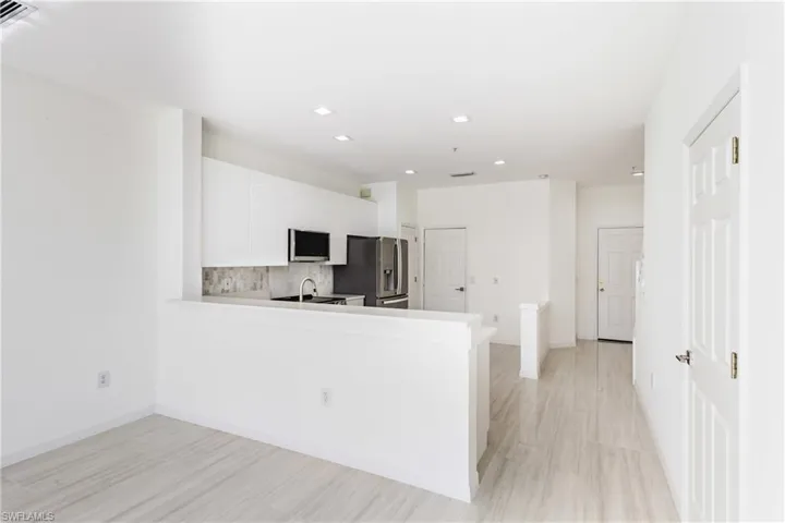 Kitchen featuring decorative backsplash, light countertops, white cabinets, and recessed lighting