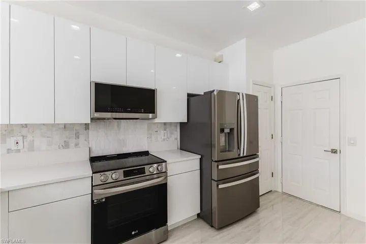 Kitchen featuring appliances with stainless steel finishes, white cabinetry, modern cabinets, and tasteful backsplash