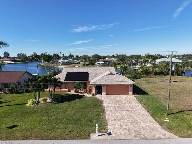 View of front facade with solar panels, a water view, and a front lawn