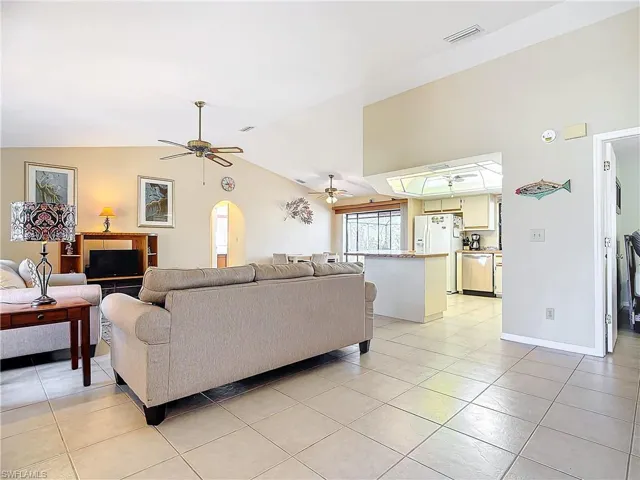 Living room featuring ceiling fan, light tile patterned flooring, and lofted ceiling