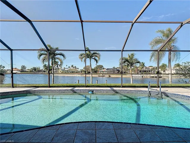 View of pool with glass enclosure, a patio area, and a water view