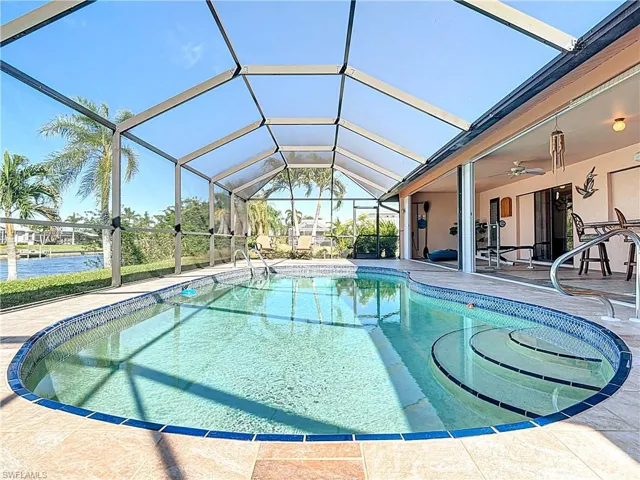 View of swimming pool featuring a lanai, a water view, ceiling fan, and a patio area