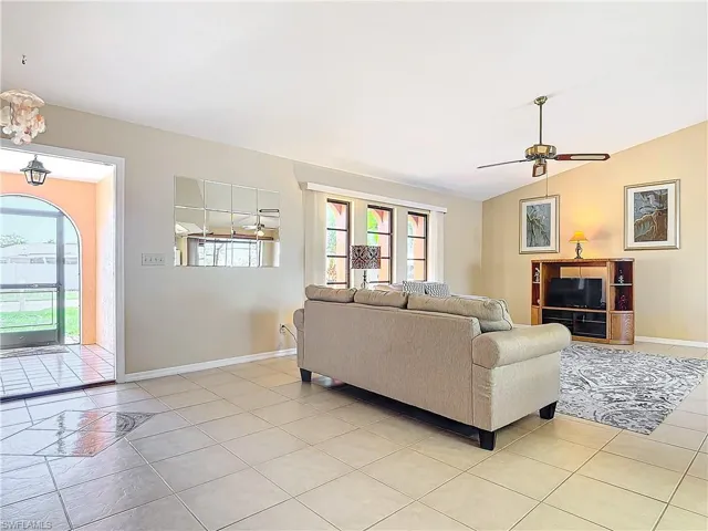 Tiled living room with ceiling fan and lofted ceiling