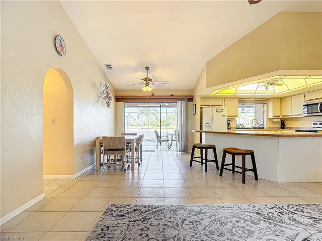 Dining room with ceiling fan, light tile patterned floors, and vaulted ceiling