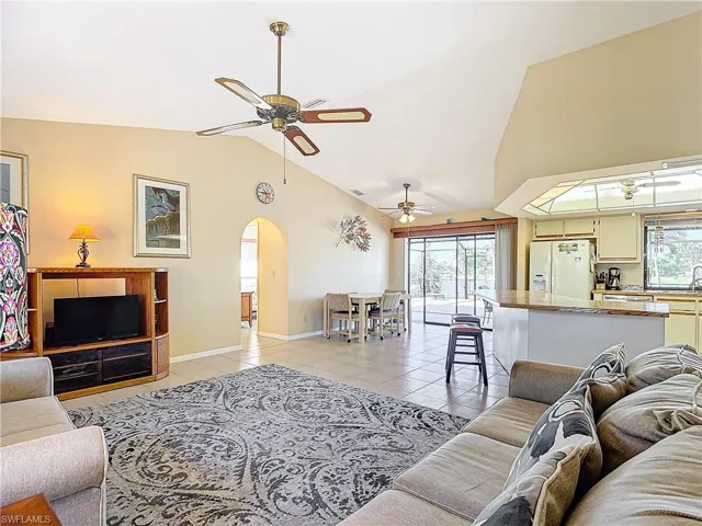 Living room with light tile patterned floors, vaulted ceiling, and ceiling fan