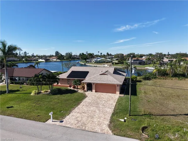 Ranch-style home featuring solar panels, a water view, a garage, and a front lawn