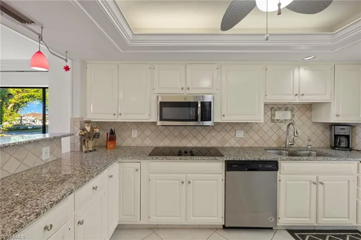 Kitchen featuring light stone countertops, ceiling fan, sink, stainless steel appliances, and light tile patterned floors
