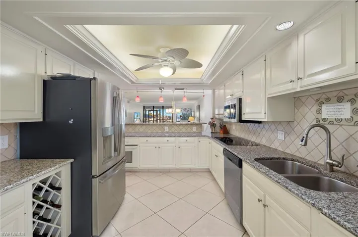 Kitchen featuring backsplash, stainless steel appliances, a raised ceiling, and sink