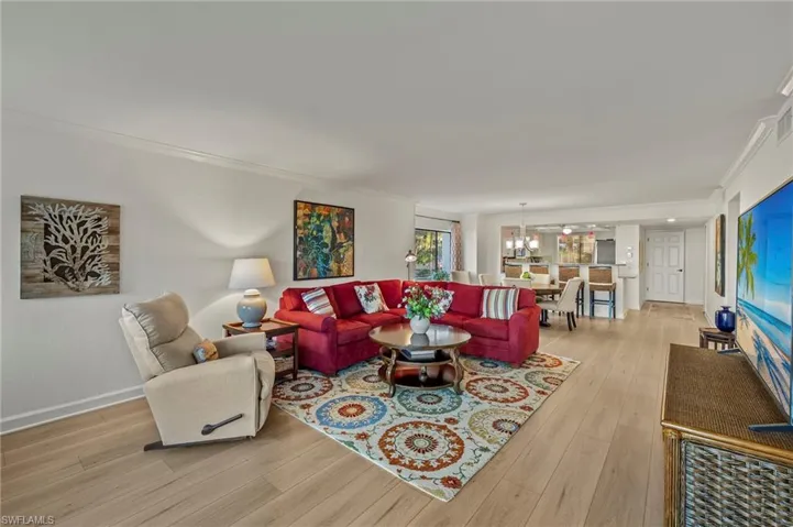 Living room with light hardwood / wood-style flooring, a notable chandelier, and ornamental molding