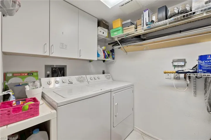 Laundry area with separate washer and dryer, light tile patterned flooring, and cabinets