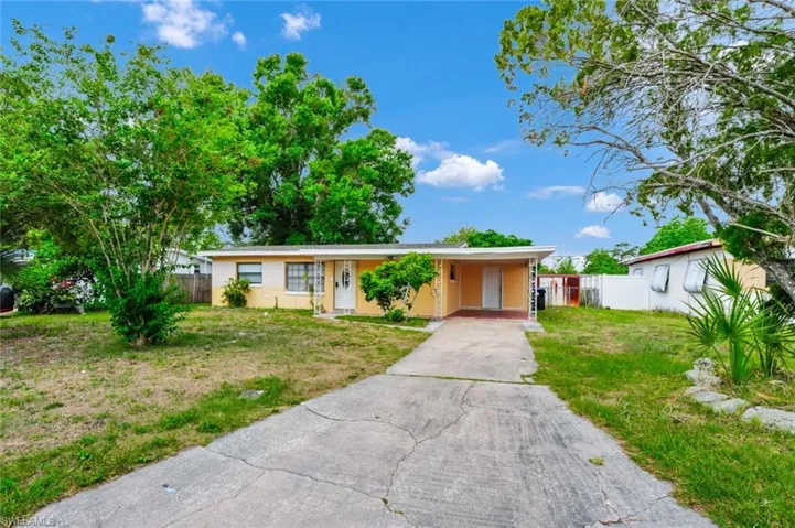 Ranch-style house featuring fence, driveway, a front yard, and a carport