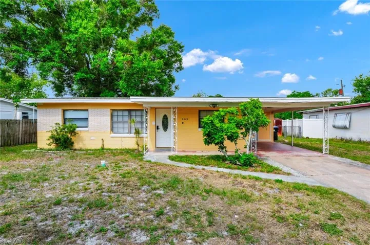 Single story home with fence, brick siding, concrete block siding, a carport, and driveway