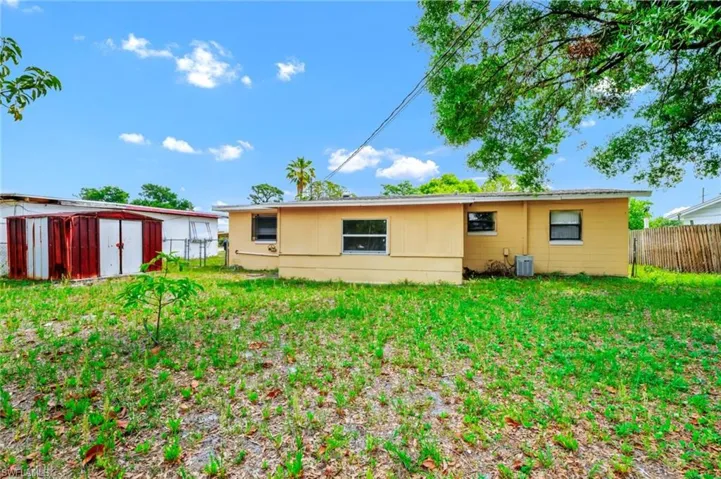 Back of property with a lawn, fence, an outbuilding, and a storage unit