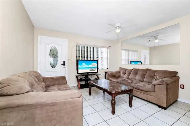 Living room with a ceiling fan, baseboards, and light tile patterned floors