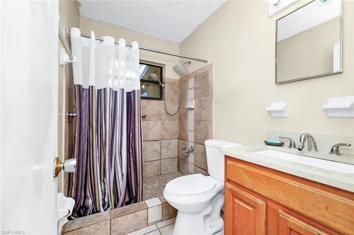 Full bath featuring vanity, tile patterned flooring, a stall shower, and toilet