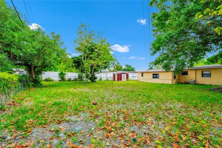 View of yard with a storage shed, fence, and an outbuilding
