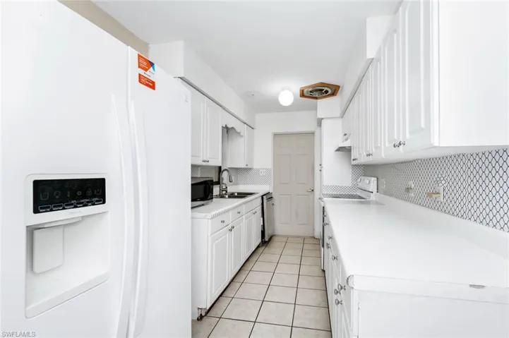 Kitchen with light countertops, tasteful backsplash, a sink, appliances with stainless steel finishes, and light tile patterned floors