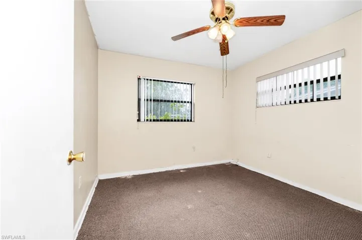 Carpeted empty room with a ceiling fan and baseboards