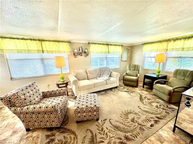 Living room featuring a healthy amount of sunlight, a textured ceiling, and tile floors