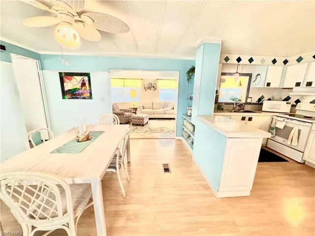 Kitchen featuring white appliances, extractor fan, ceiling fan, and light hardwood / wood-style flooring