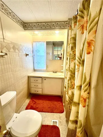 Bathroom featuring tile flooring, tile walls, toilet, and vanity