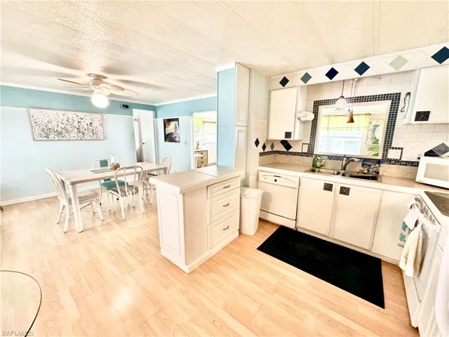 Kitchen featuring light hardwood / wood-style flooring, white appliances, backsplash, sink, and ceiling fan