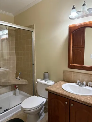 Bathroom featuring vanity, ornamental molding, toilet, and an enclosed shower