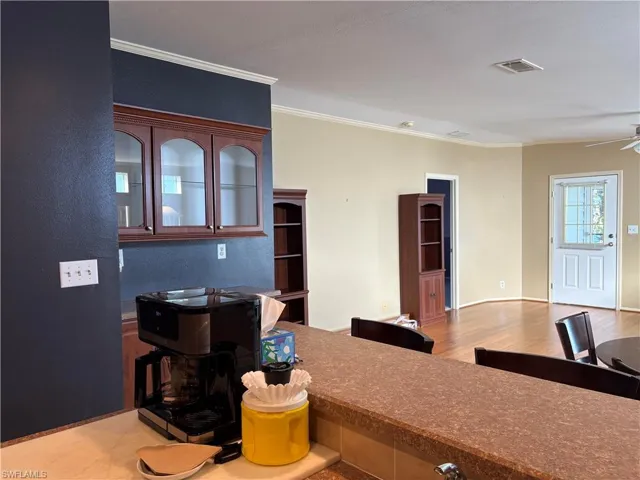 Kitchen with ornamental molding, wood-type flooring, and ceiling fan