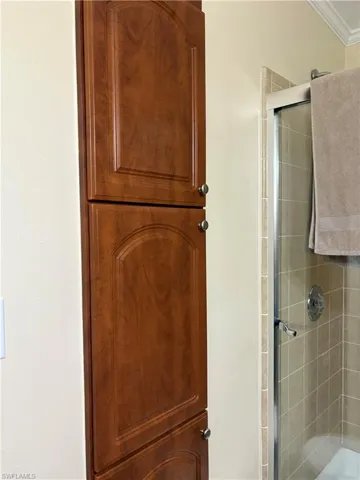 Bathroom with a shower with door and crown molding