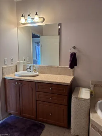 Bathroom with vanity, a relaxing tiled tub, and tile patterned flooring