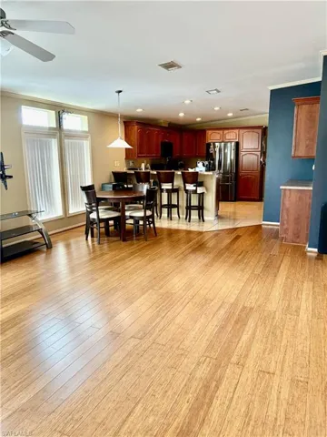 Dining space with ceiling fan, ornamental molding, and light wood-type flooring
