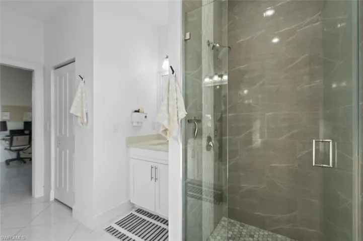 Full bath featuring marble finish floor, baseboards, vanity, and a marble finish shower