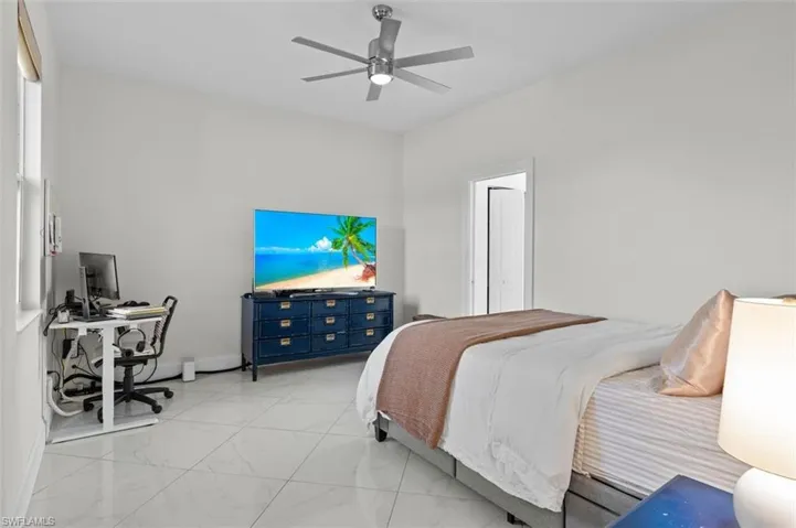 Bedroom featuring a ceiling fan, marble finish floor, and baseboards