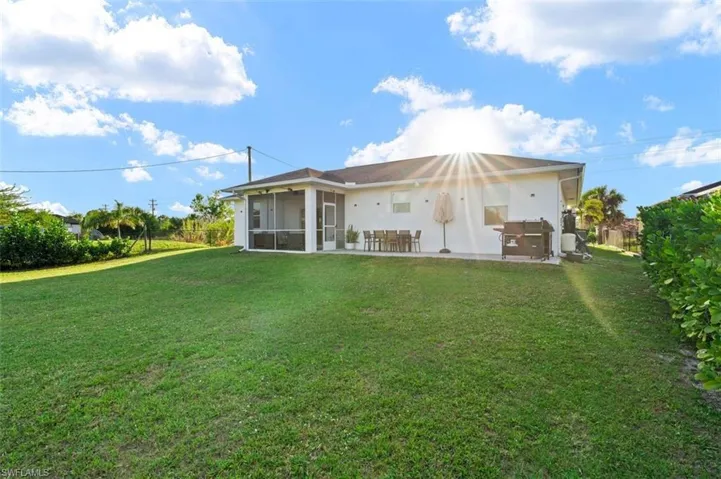 Back of property featuring a sunroom, a patio, and a yard
