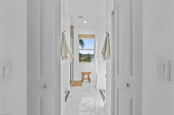 Hallway with light tile patterned floors, visible vents, and baseboards