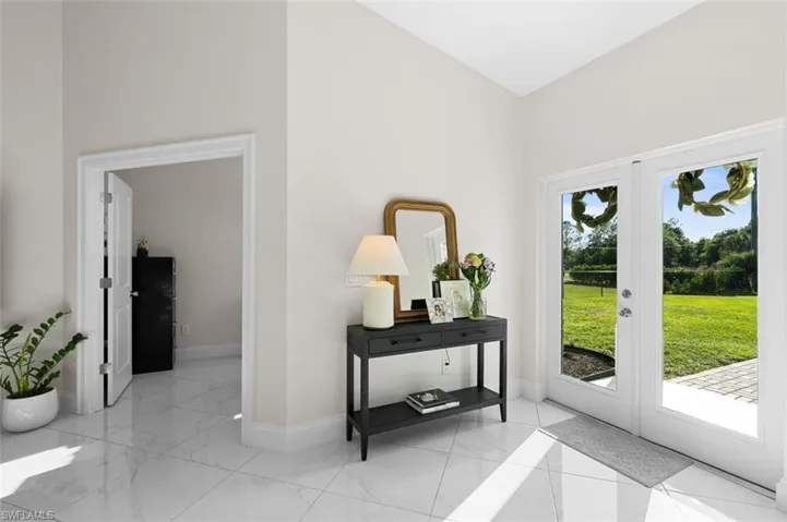 Doorway featuring french doors, a healthy amount of sunlight, marble finish floor, and baseboards