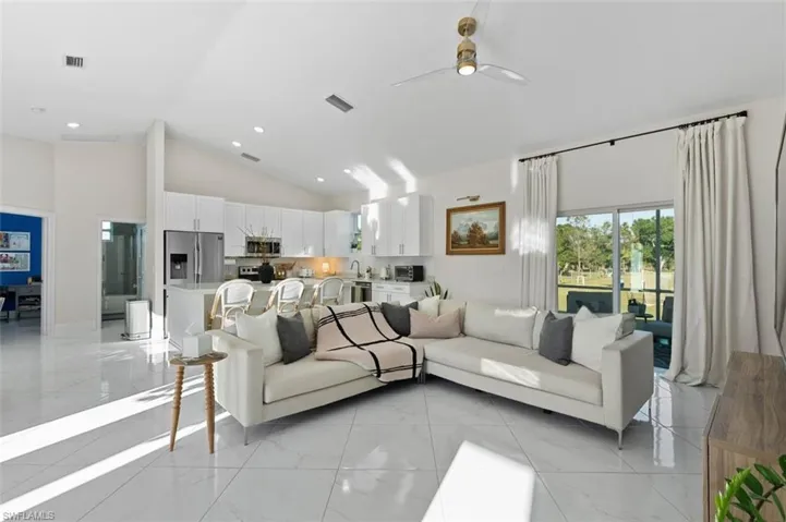 Living room featuring high vaulted ceiling, marble finish floor, visible vents, and ceiling fan