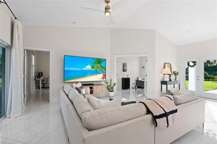Living area with lofted ceiling, marble finish floor, and ceiling fan