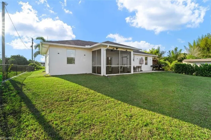 Back of property featuring a yard, fence, a sunroom, and stucco siding