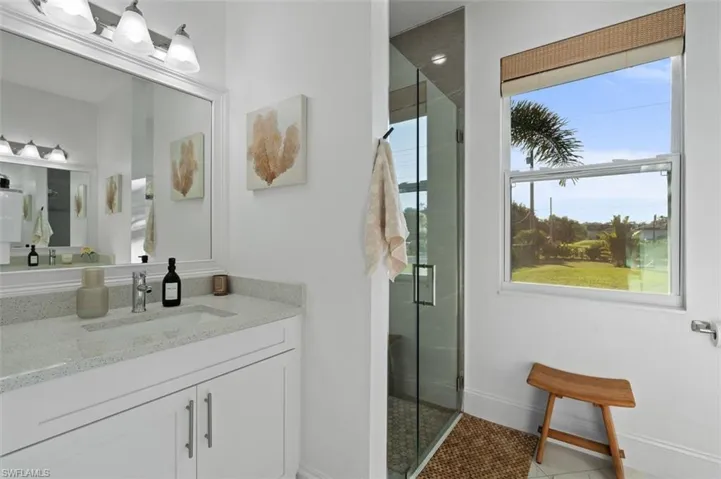 Bathroom featuring a healthy amount of sunlight, a shower stall, and vanity