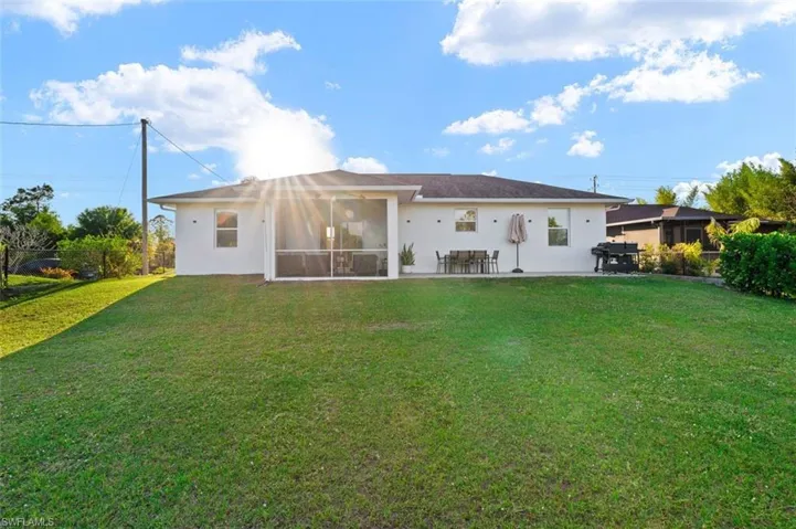 Back of property featuring a sunroom, a lawn, fence, and stucco siding
