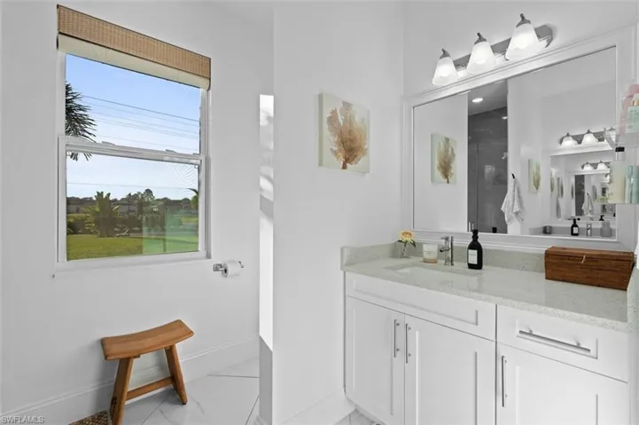 Bathroom featuring a stall shower, baseboards, marble finish floor, and vanity